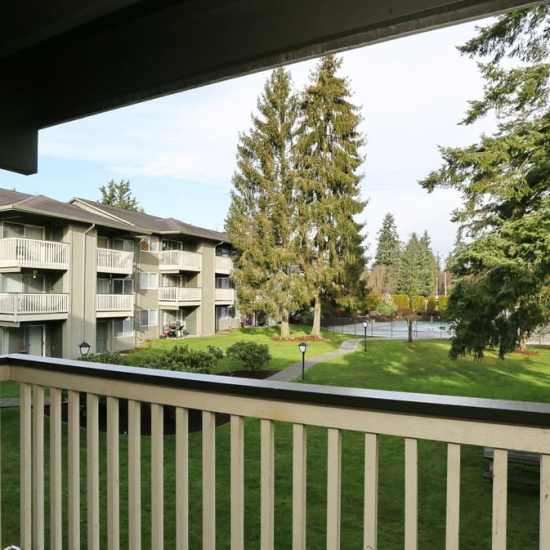 View of lush grounds and swimming pool from a private patio at Bluffs at Evergreen in Everett, Washington