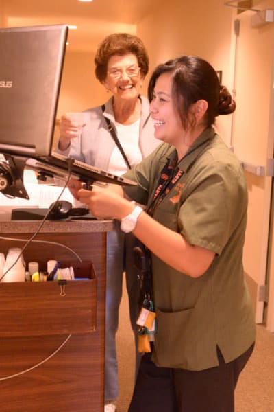 Resident talking to a nurse about medication at a computer at Quail Park of Lynnwood in Lynnwood, Washington