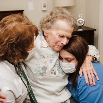 Resident hugging caretakers at an English Meadows campus