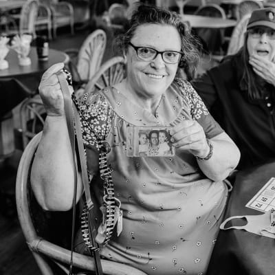 Resident at Bingo Night showing off a photo of her family at Cascade Park Vista Assisted Living in Tacoma, Washington