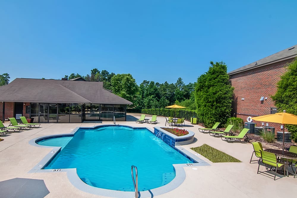 Resident pool featuring a water feature, lots of pool chairs, and covered tables at Greenleaf Apartments in Phenix City, Alabama