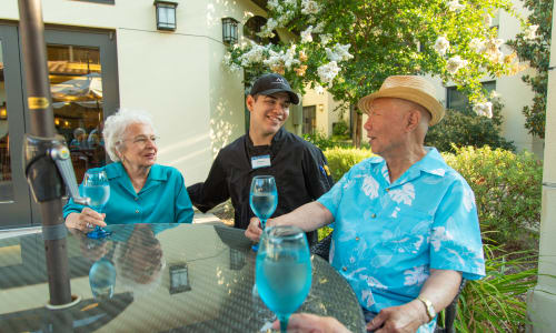 A staff member helping a resident couple at a Merrill Gardens community.