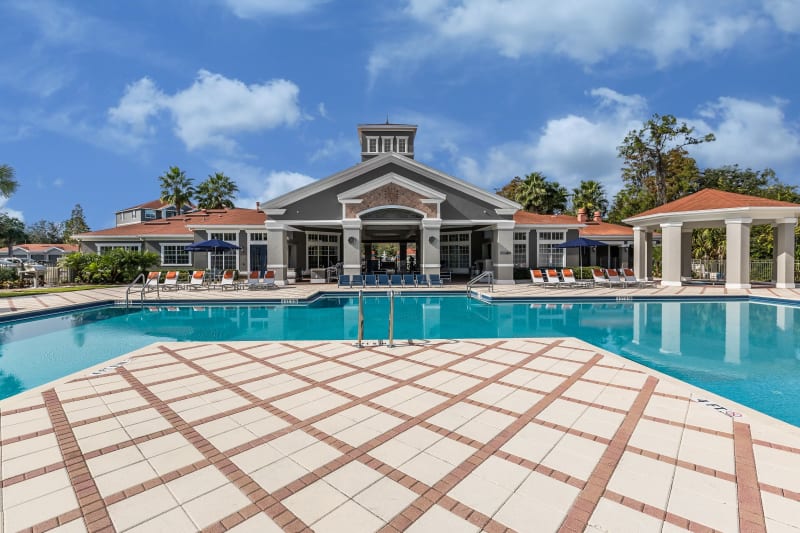 Resort-style swimming pool flanked by chaise lounge chairs and lush vegetation at The Aspect in Kissimmee, Florida
