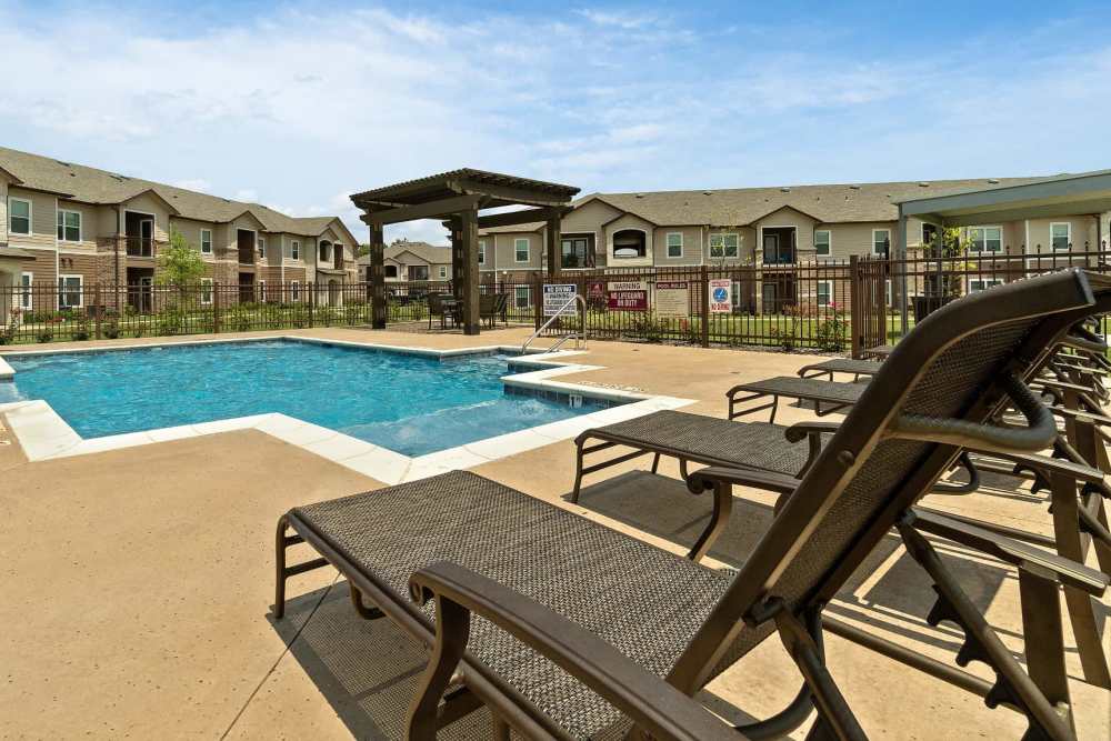 Resort-style swimming pool with luxurious lounge chairs at Pine Creek in Paris, Texas