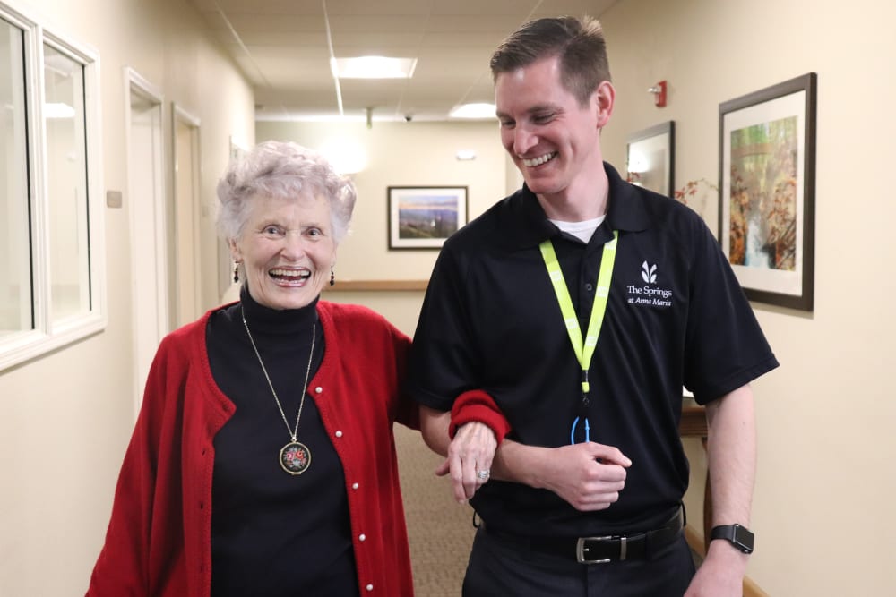 Resident and caretaker walking a hallway together at The Springs at Anna Maria in Medford, Oregon