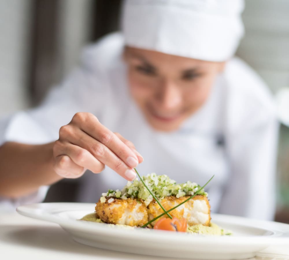 A delicious plate of food being garnished by a chef at Holden of Bellevue in Bellevue, Washington.
