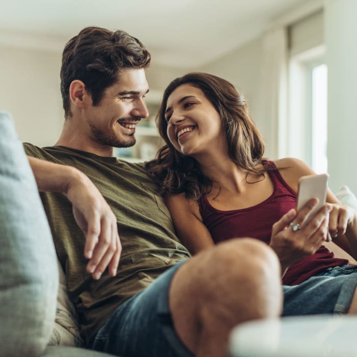 A couple sit on a sofa in their apartment at Attain at Bradford Creek, Huntsville, Alabama