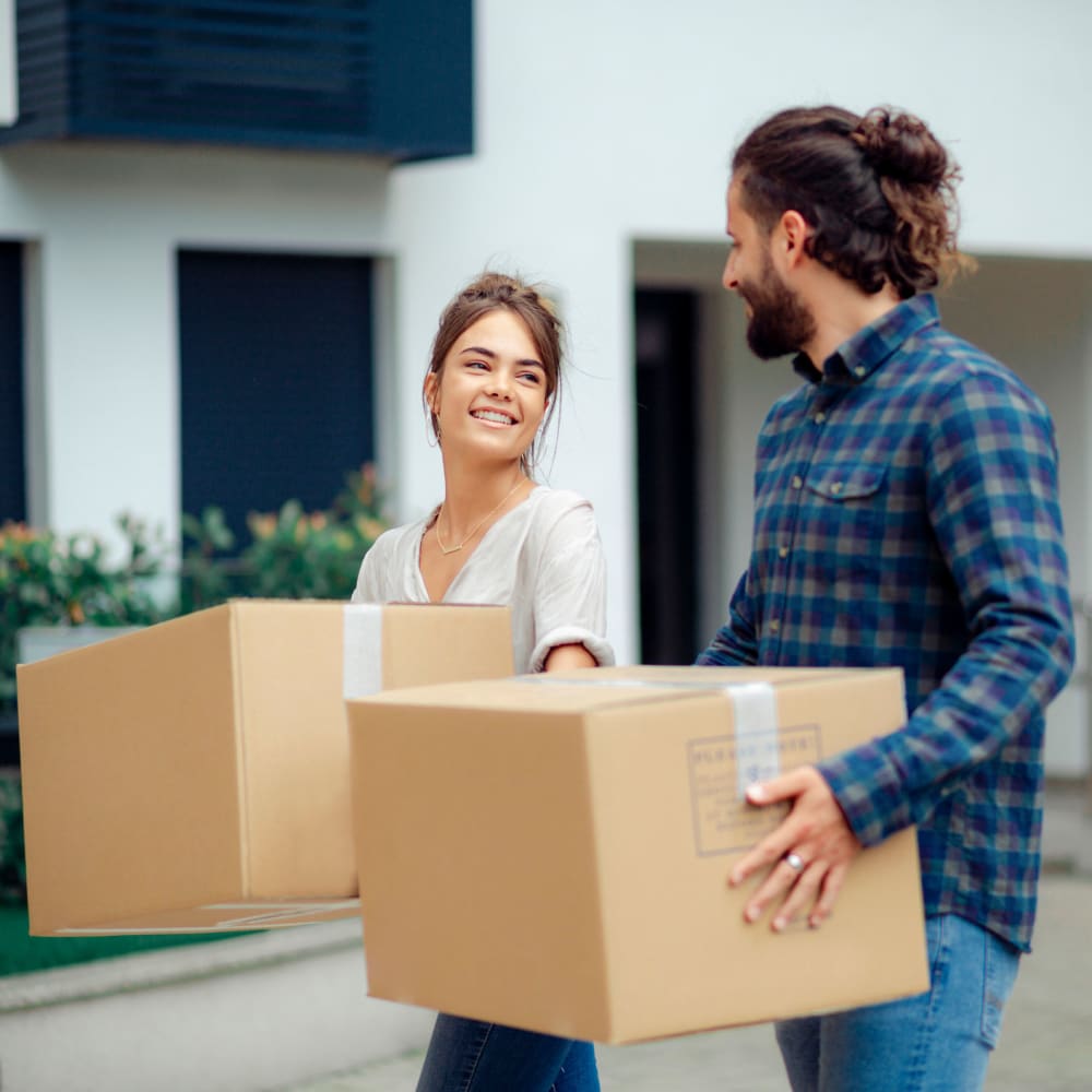 Two people carry boxes to their storage unit