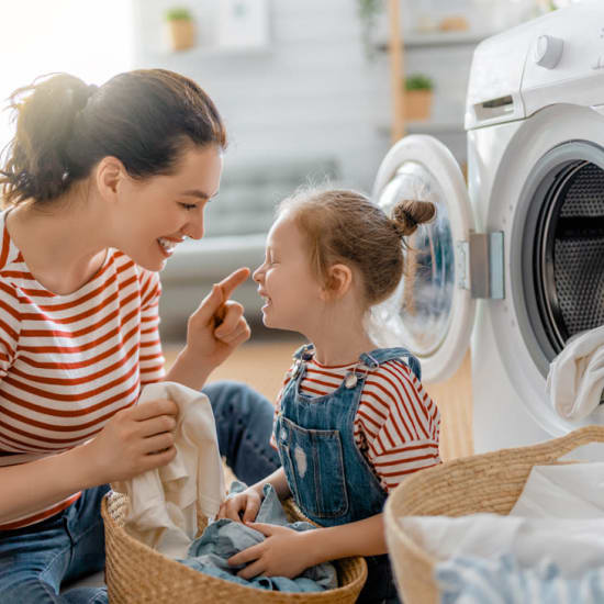 Laundry facilities are available onsite. A mom and daughter are doing laundry together at Quailwood Apartments in Stockton, California