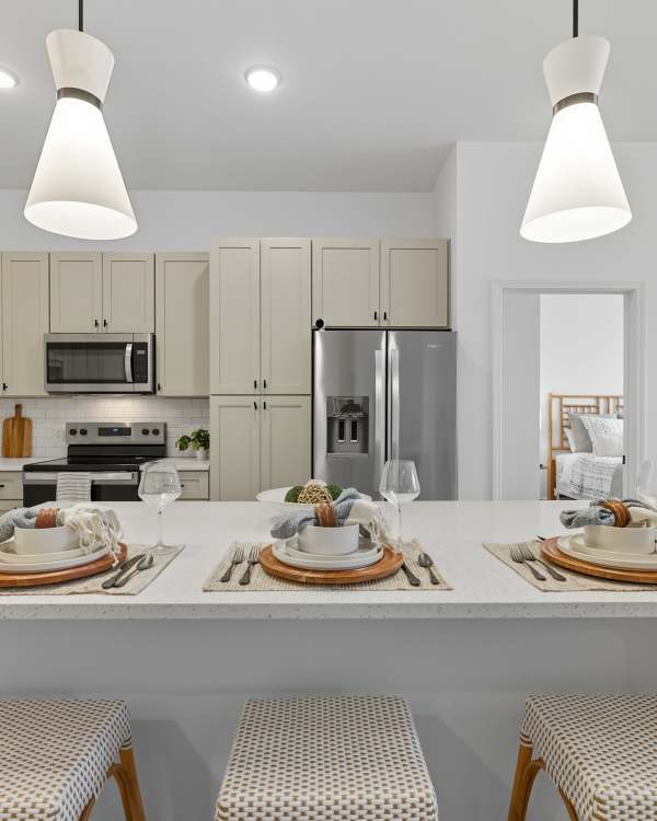 Modern kitchen with white cabinets and bar seating at Wilton Palm Coast in Palm Coast, Florida