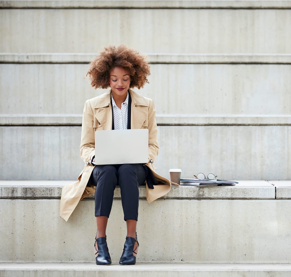 Resident working on her laptop on the steps outside her office near Sofi Warner Center in Woodland Hills, California