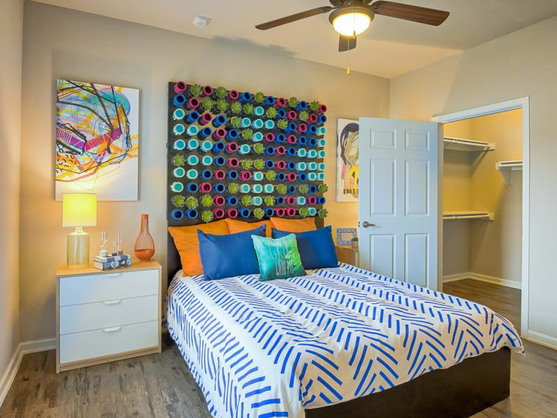 Model bedroom with wood-style flooring and a walk-in closet at Creekside at Kenney's Fort in Round Rock, Texas