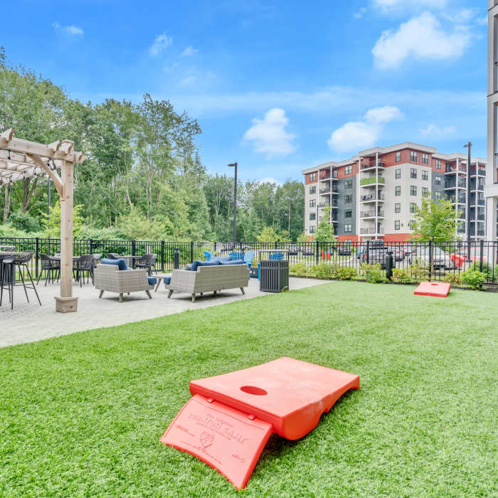 Red cornhole boards on green grass at Latitude at South Portland in Portland, Maine