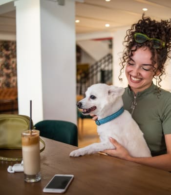 A resident holds her dog at a table while drinking coffee at University Lofts Downtown, Jonesboro, Arkansas