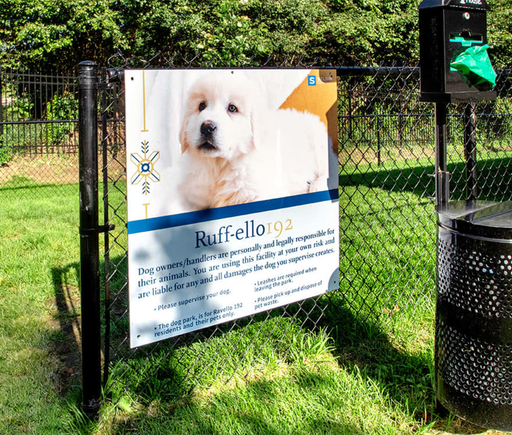 A large poster of a dog attached to a park fence at Ravello 192 in Elkhorn, Nebraska