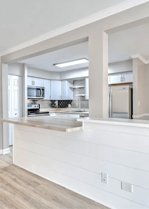 Open kitchen with wooden cabinet and access to living room at Terraces of Elk Grove in Elk Grove Village, Illinois