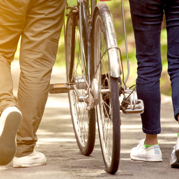 Resident couple taking a leisurely walk with their bikes through the neighborhood at Mirador & Stovall at River City in Jacksonville, Florida