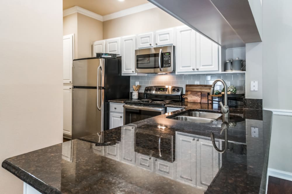 Bright kitchen with granite counters and stainless steel appliances at Marquis at Carmel Commons in Charlotte, North Carolina