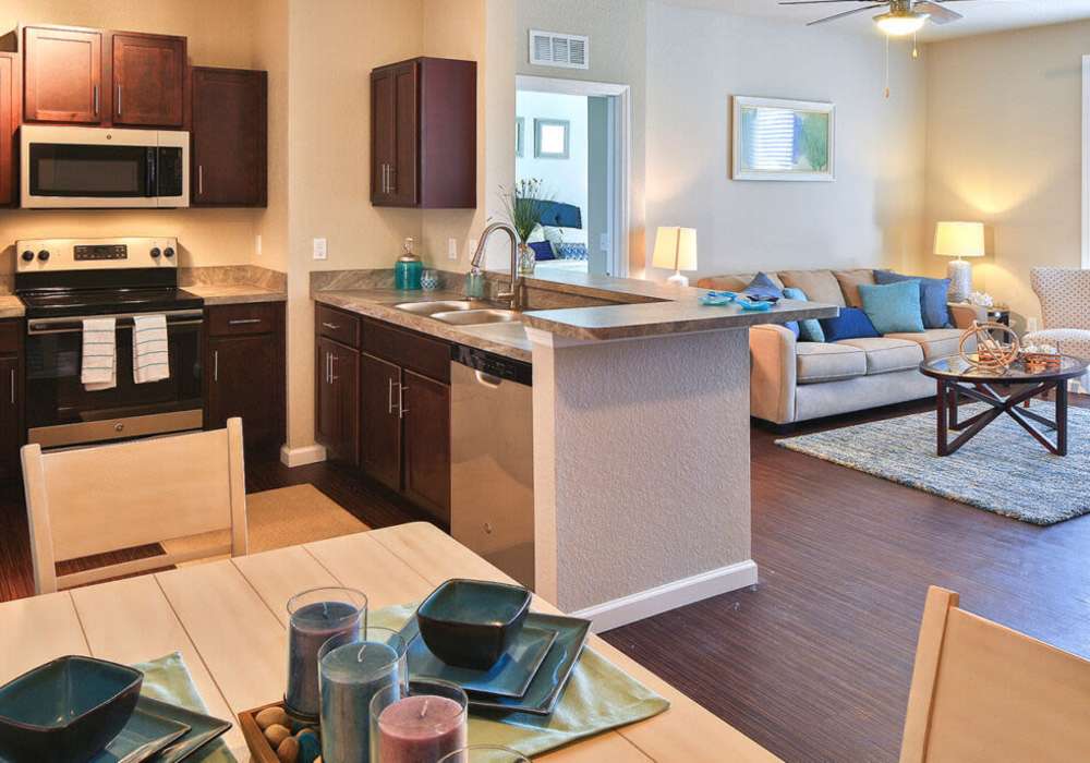 Modern kitchen connected to a cozy sunlit living room at Messina Luxury Apartments in New Smyrna Beach, Florida