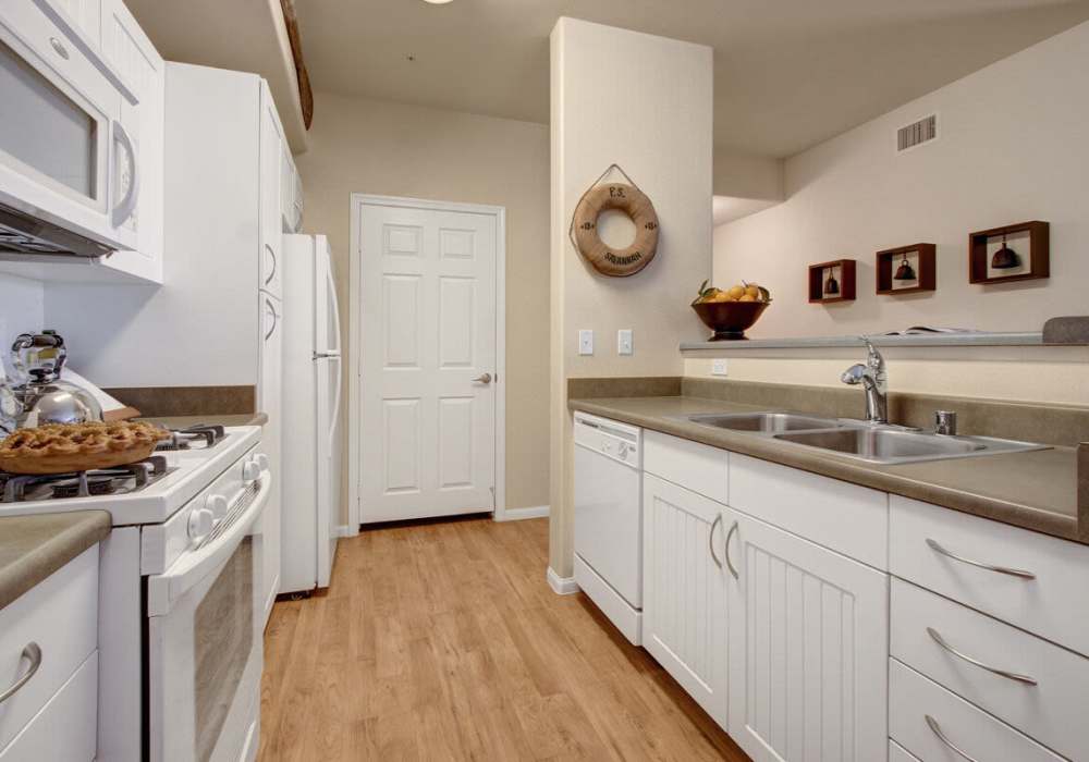 Fully equipped kitchen with white wood cabinets and Appliances at at Rivers Edge in Lake Elsinore, California
