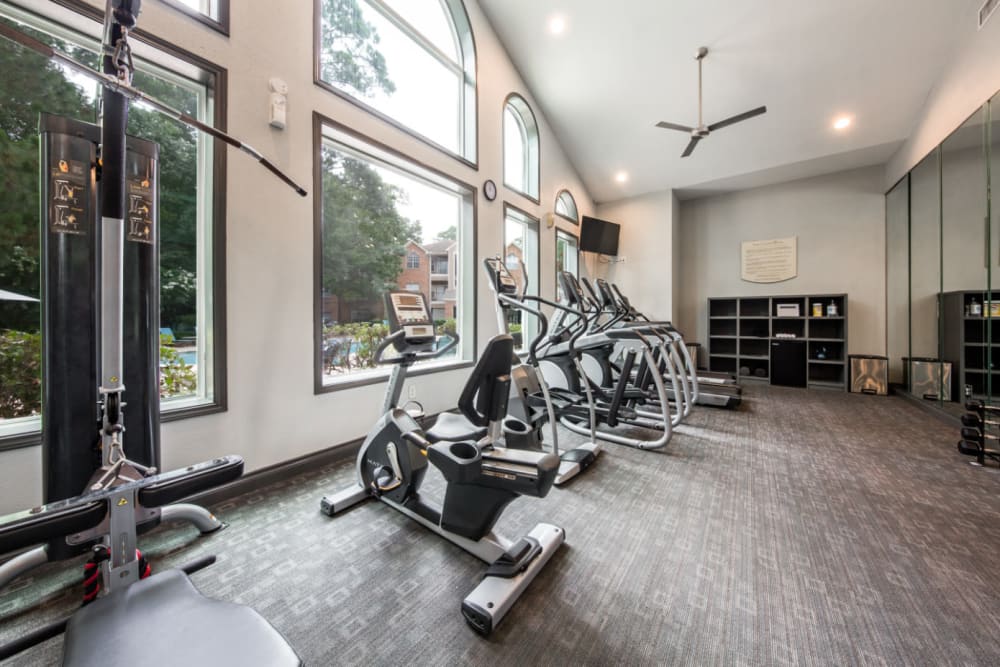 Exercise bikes in fitness room overlooking pool at Marquis at Kingwood in Kingwood, Texas