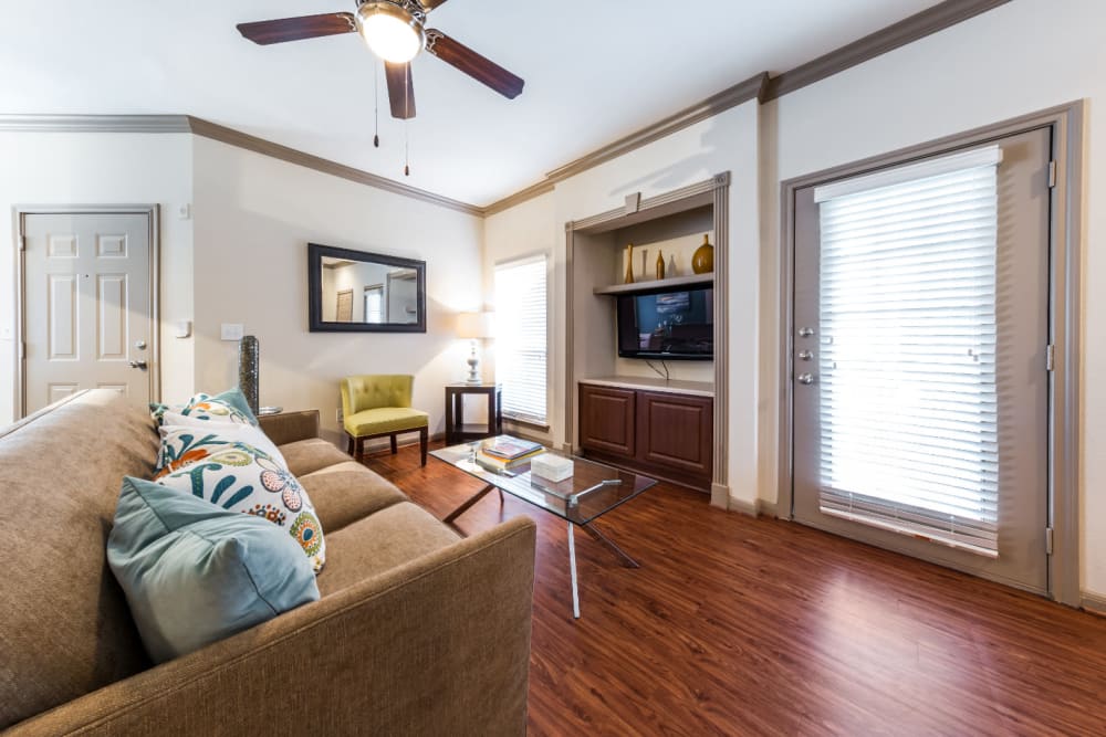 Bright living room with built in entertainment center space and door to private balcony at Marquis on Park Row in Houston, Texas