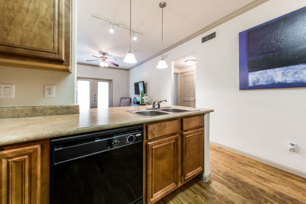 Bright kitchen with wood cabinets and flooring at Marquis at Clear Lake in Webster, Texas