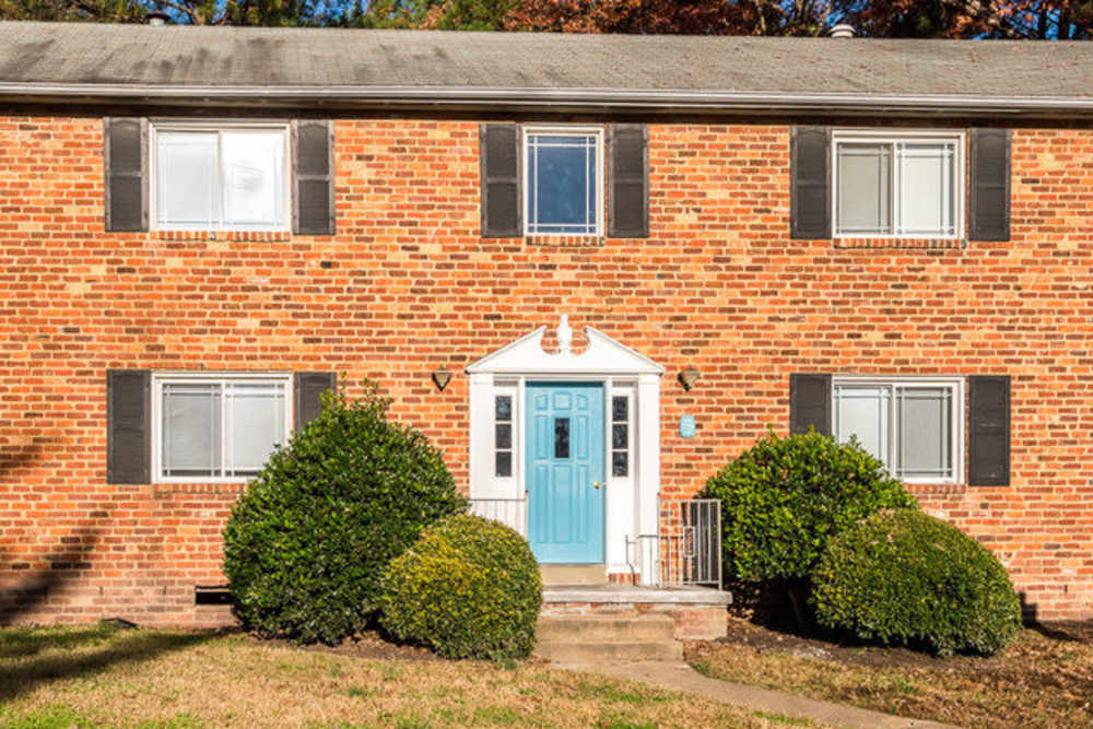 View of exterior of apartments and green lawn at Deering Manor in Richmond, Virginia