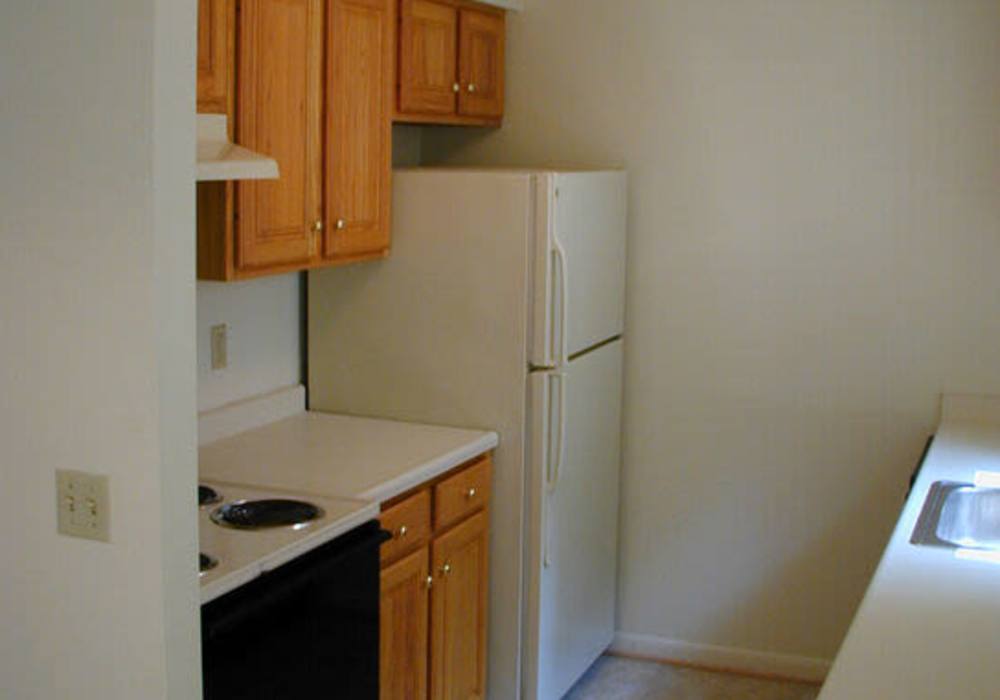 Cozy kitchen with wood-style cabinets at Jefferson Manor Townhomes in Fairport, New York