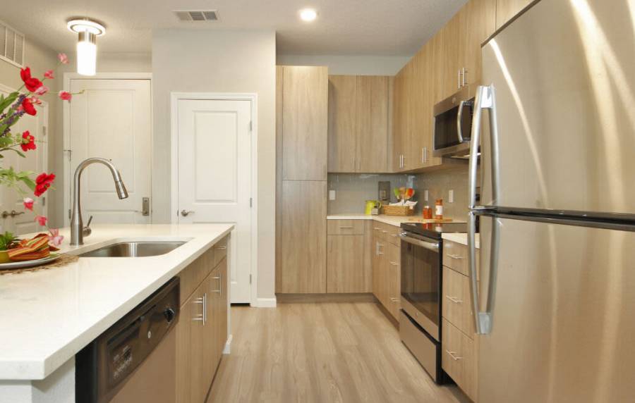 Sleek modern kitchen with stainless steel appliances and wooden cabinetry at Messina Luxury Apartments in New Smyrna Beach, Florida