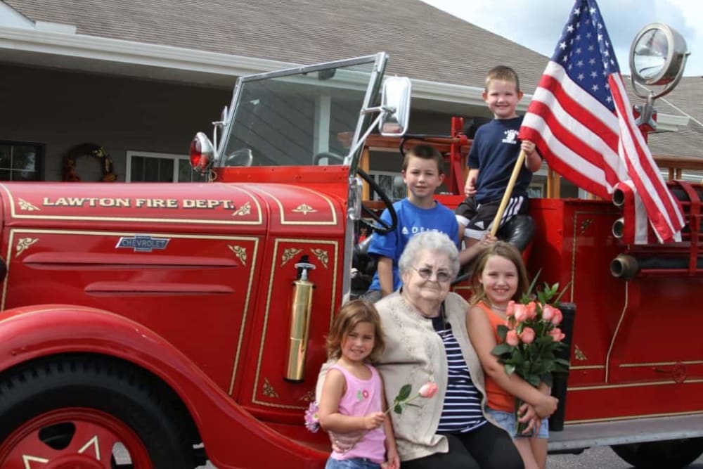 Resident and family pose with antique fire truck visiting Lawton Senior Living in Lawton, Iowa.