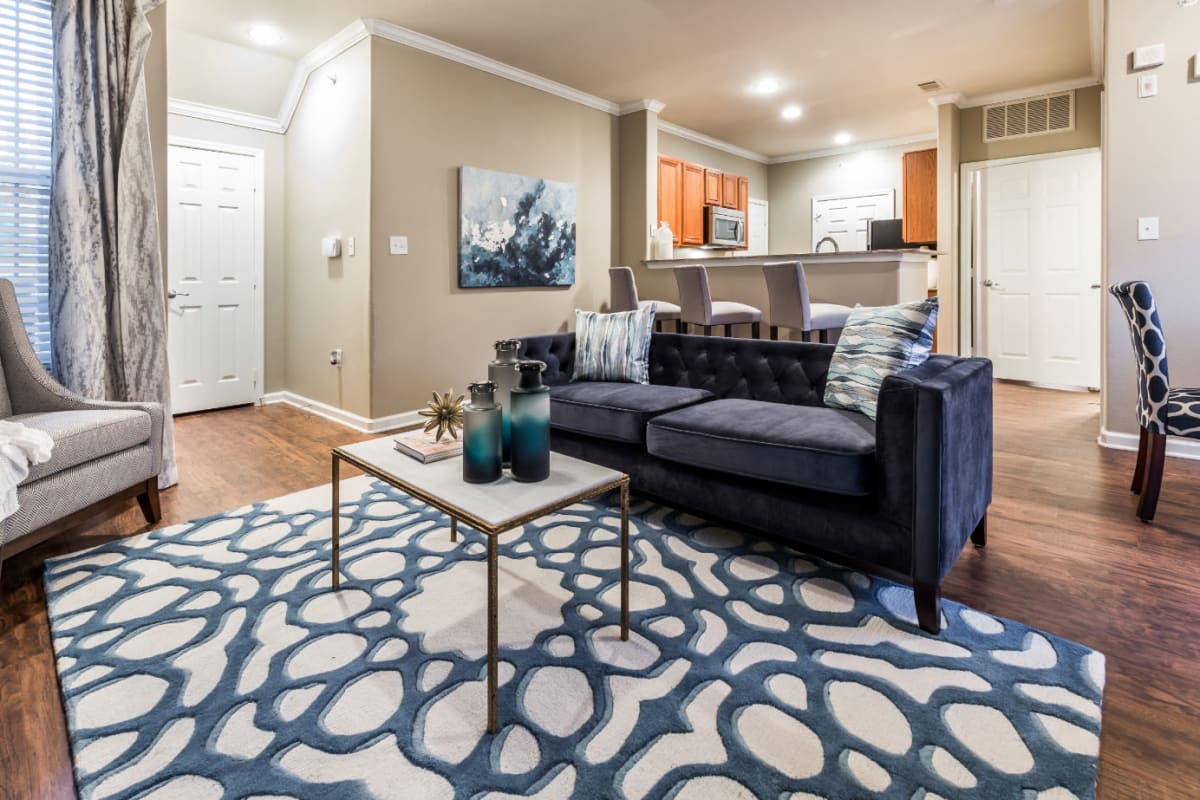 Modern style living room with full size couch, wood flooring, and sitting chair at Marquis at The Cascades in Tyler, Texas