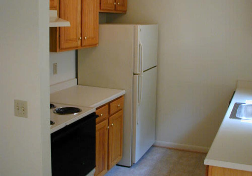 Compact kitchen with oak cabinets and appliances at Jefferson Manor Townhomes in Fairport, New York