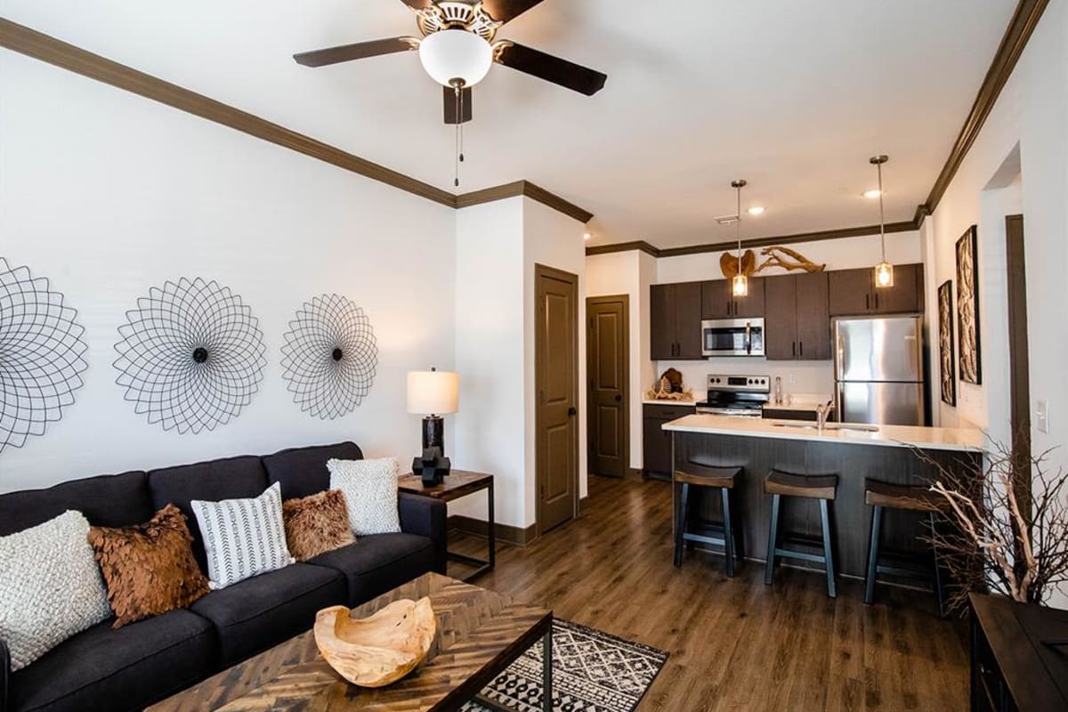 Wood-style flooring in an apartment living room and kitchen at Thrive at Creekside in Parkville, Missouri