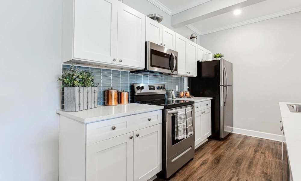 Modern kitchen with stainless steel appliances, granite countertops, and wood-style flooring at Everett at Port Wentworth in Port Wentworth, Georgia