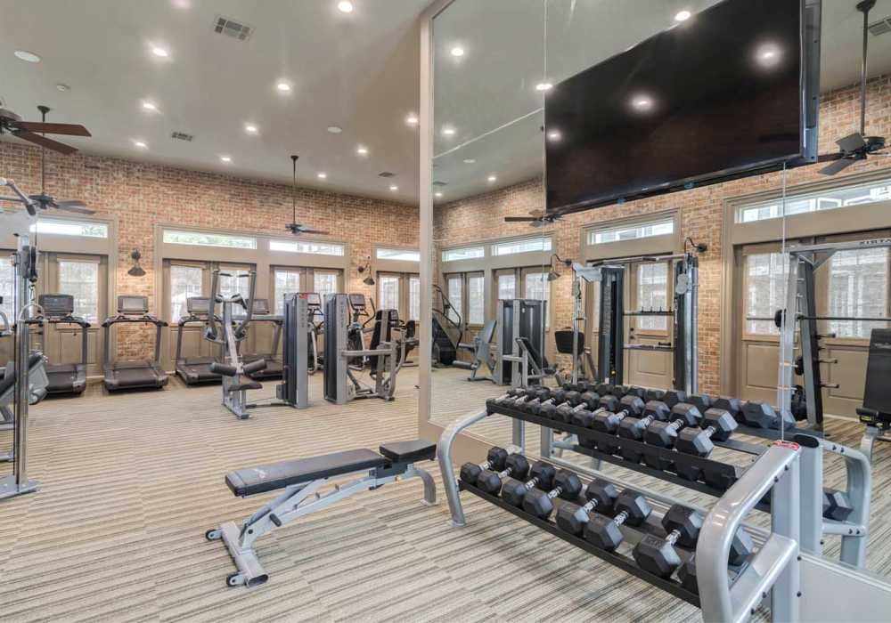 Fitness center with dumbbell rack, weight machines and hardwood flooring at Southfork Lake in Manvel, Texas