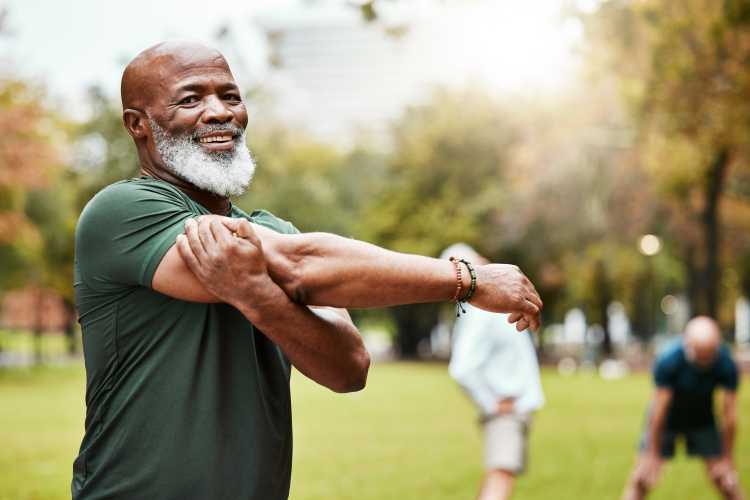 Man stretching on a green lawn outdoors, enjoying fresh air and exercise at Watermere Highlands at Watermere Highlands in Arlington, Texas