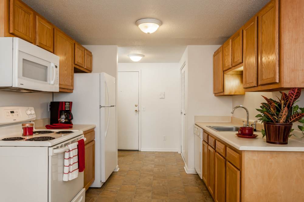 Kitchen with oak cabinets and white appliances at King's Court Manor Apartments in Rochester, New York