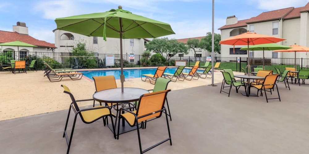 Umbrella covered tables and chairs by the pool at Villas de Toscana in San Antonio, Texas