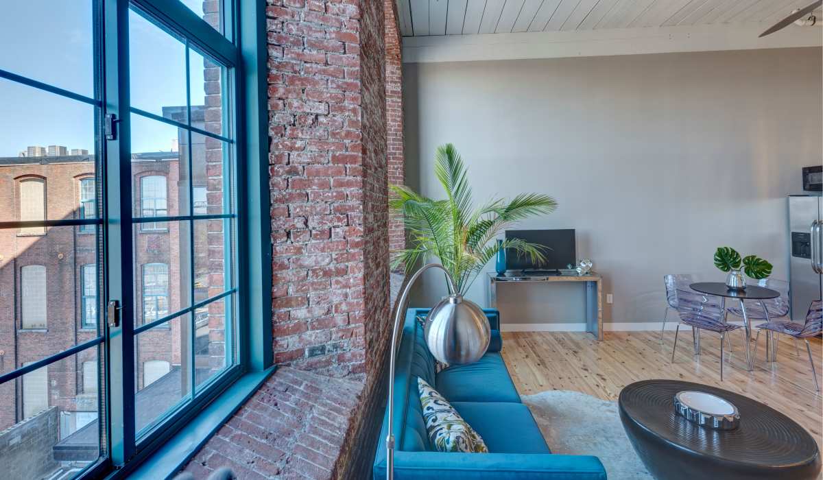 Luxury curved floor lamp beside blue couch with pillows at Commonwealth Landing Lofts in Fall River, Massachusetts