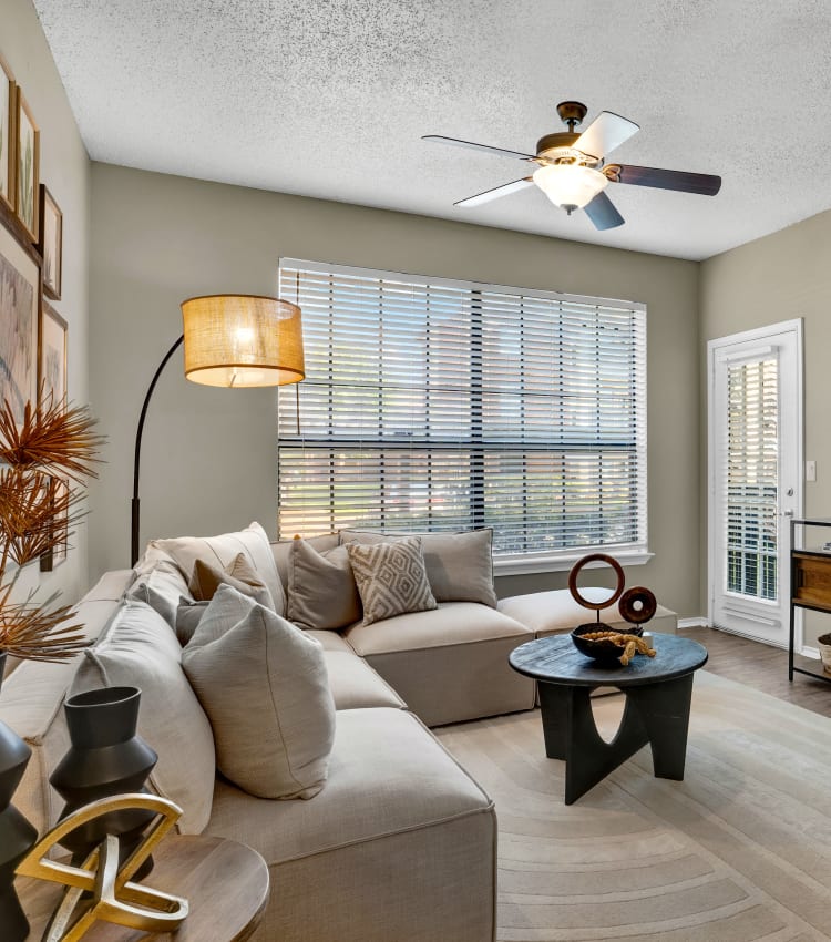 Living room with ceiling fan and large window at Carrollton Park of North Dallas in Dallas, Texas