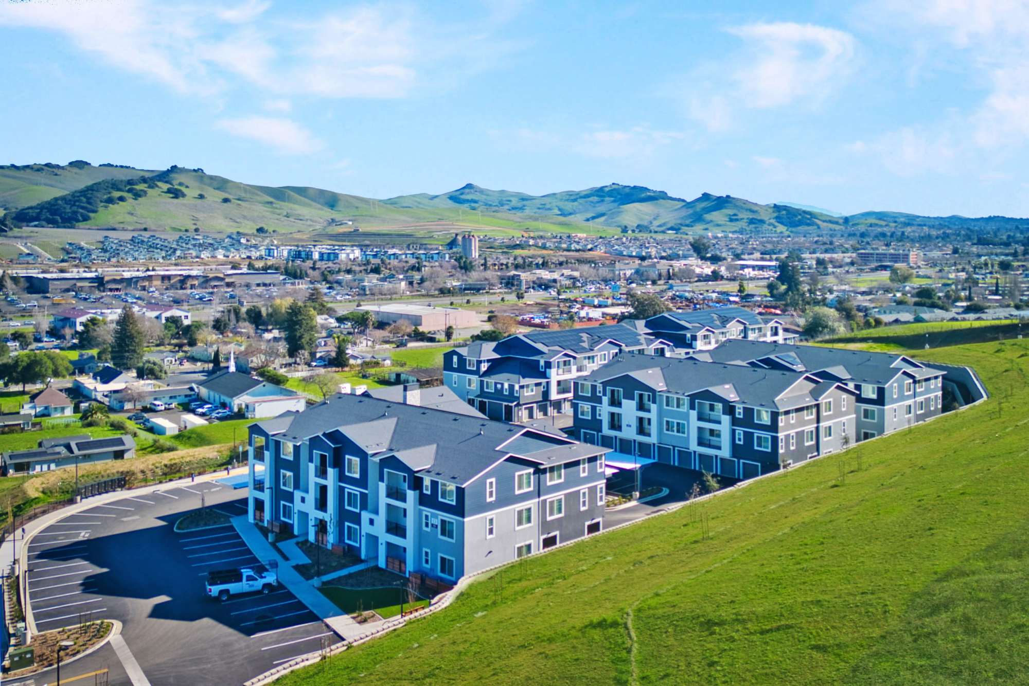 Aerial view of modern apartment community surrounded by green hills and open space at Domaine at Napa Junction in American Canyon, California
