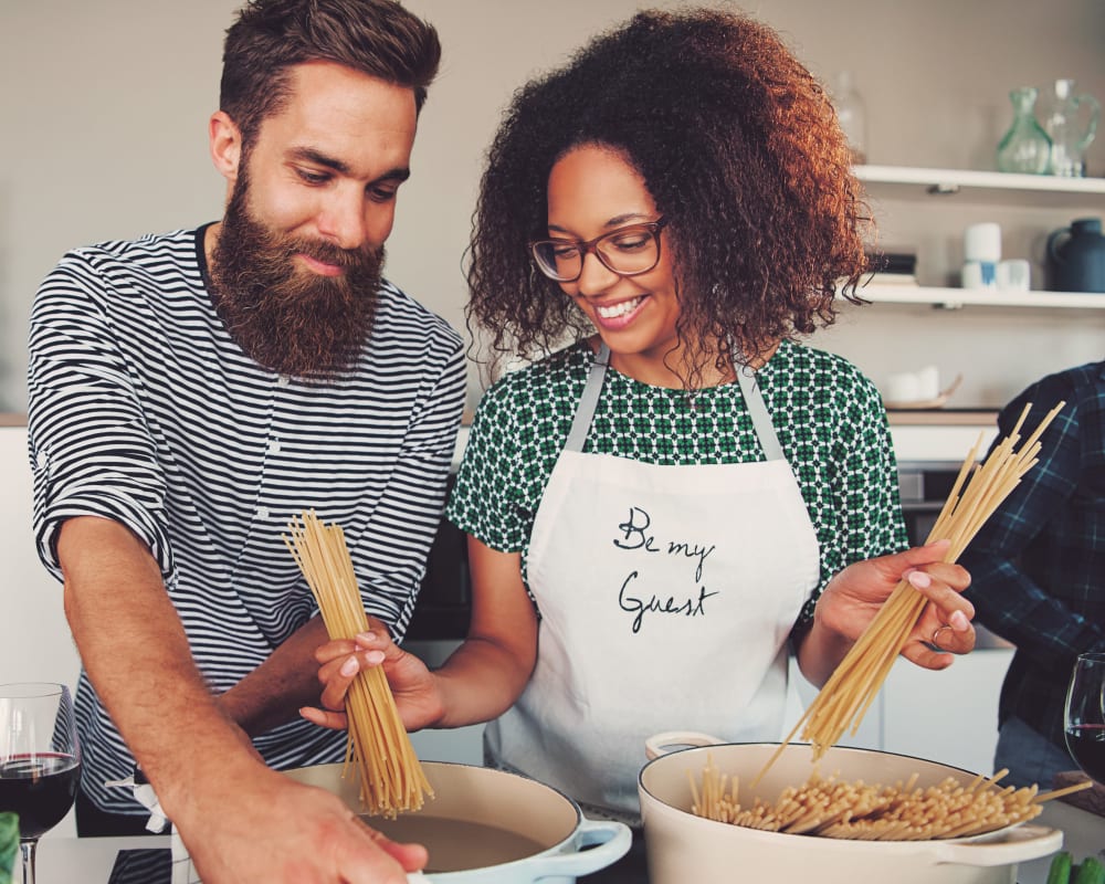 Happy couple making pasta in their fully equipped kitchen at Haven Apartment Homes in Kent, Washington