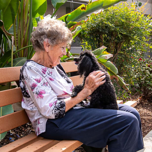 A woman outside with her dog at Pacifica Senior Living Bonita in Chula Vista, California