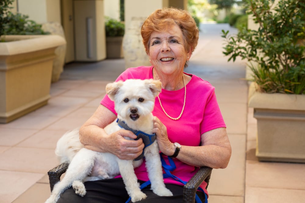 Resident holding puppy at Merrill Gardens at Huntington Beach