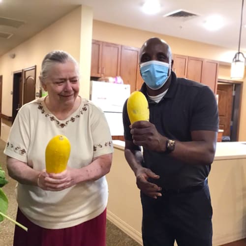Team member with a resident holding gourds at Oxford Glen Memory Care at Grand Prairie in Grand Prairie, Texas