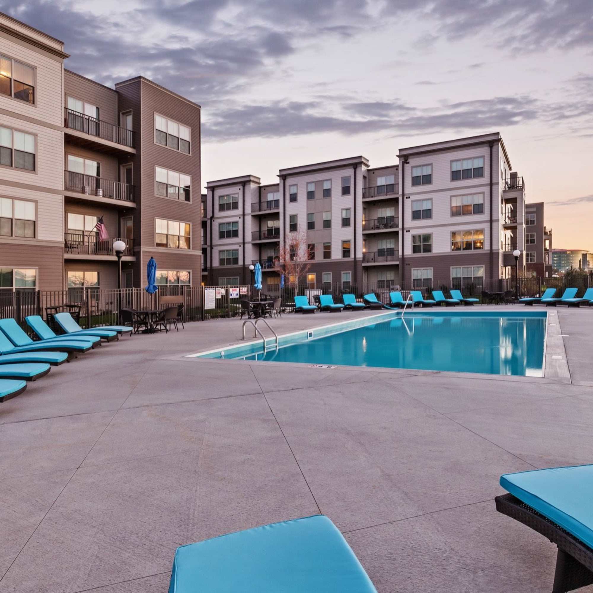 Resort-style pool surrounded by lounge chairs and modern apartment buildings with balconies at Water Street Apartments in Dayton, Ohio
