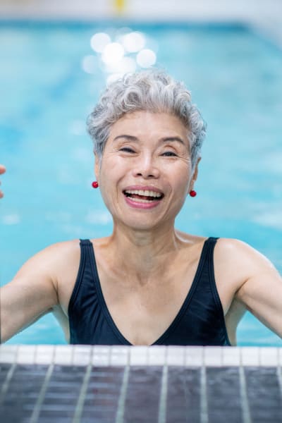 Resident climbing out of a pool using a ladder at Quail Park of Lynnwood in Lynnwood, Washington