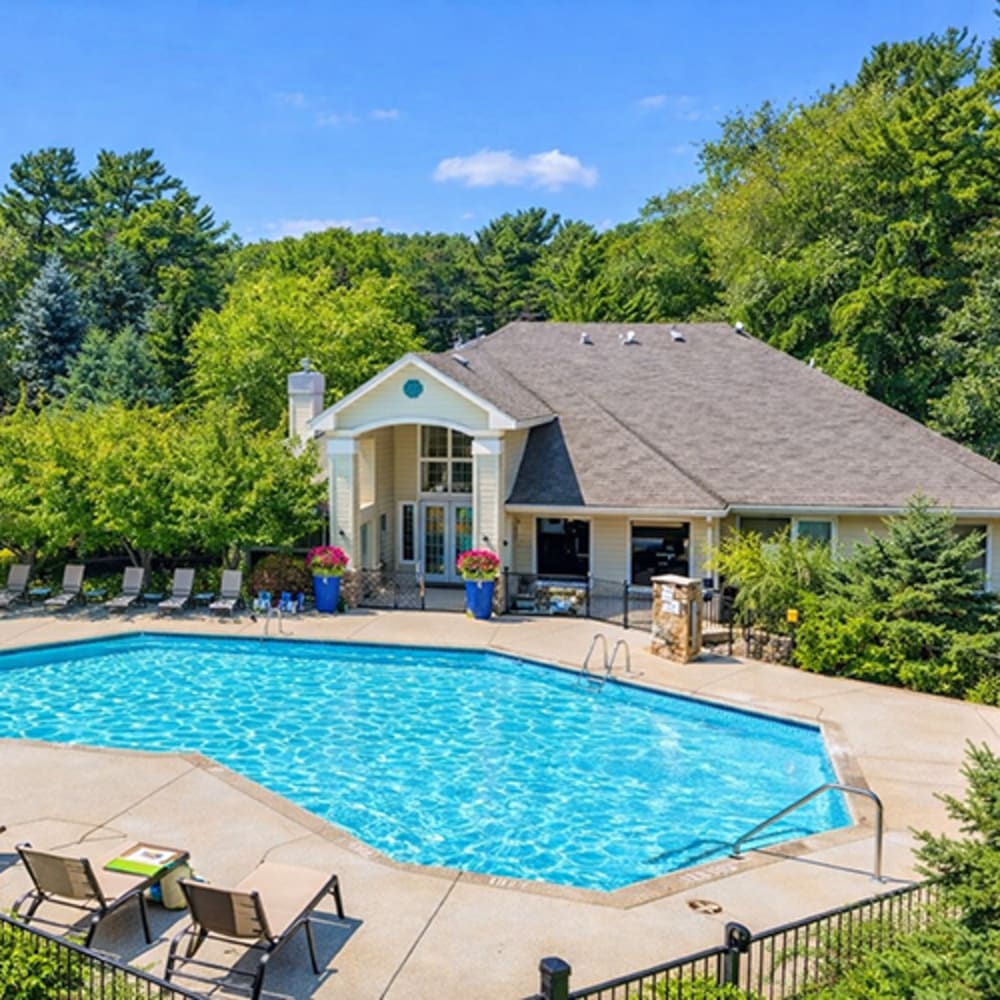 Resort-style pool surrounded by lounge chairs and lush greenery at 43 North Apartments in Grand Haven, Michigan