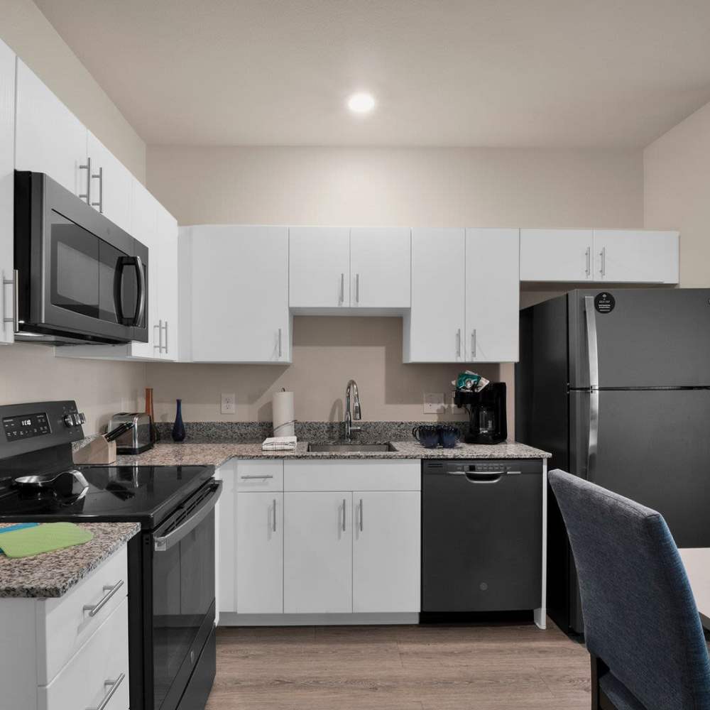 A modern kitchen showcasing the wooden cabinetry and hardwood flooring at WaterWalk Charlotte - Arrowood in Charlotte, North Carolina